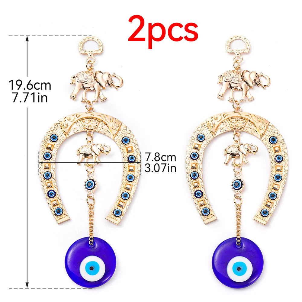 Two gold-colored horseshoe wall hangings featuring elephant charms and blue eye pendants.