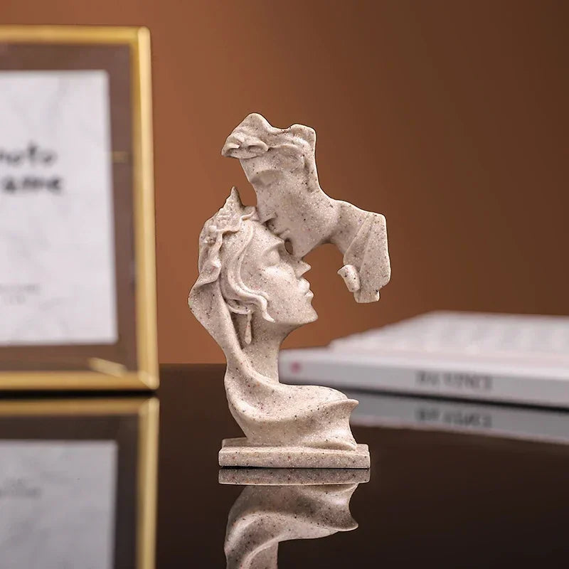 Statue en résine claire de deux figures s'étreignant, se reflétant sur une surface sombre.
