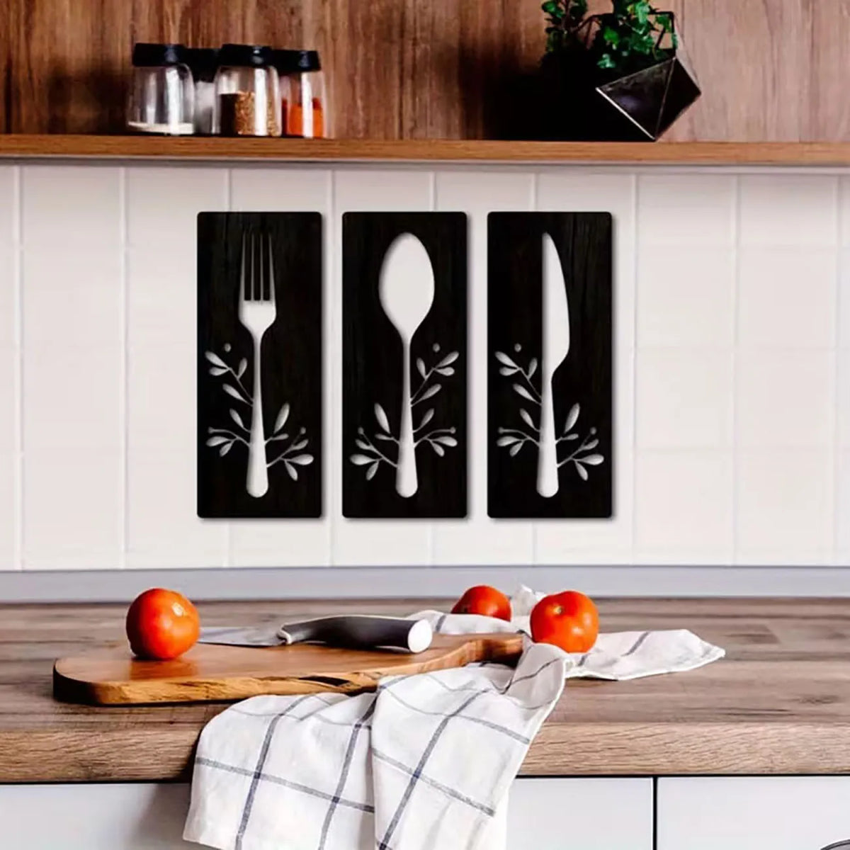A set of three wooden utensils displayed as wall decor against a white tiled backsplash.
