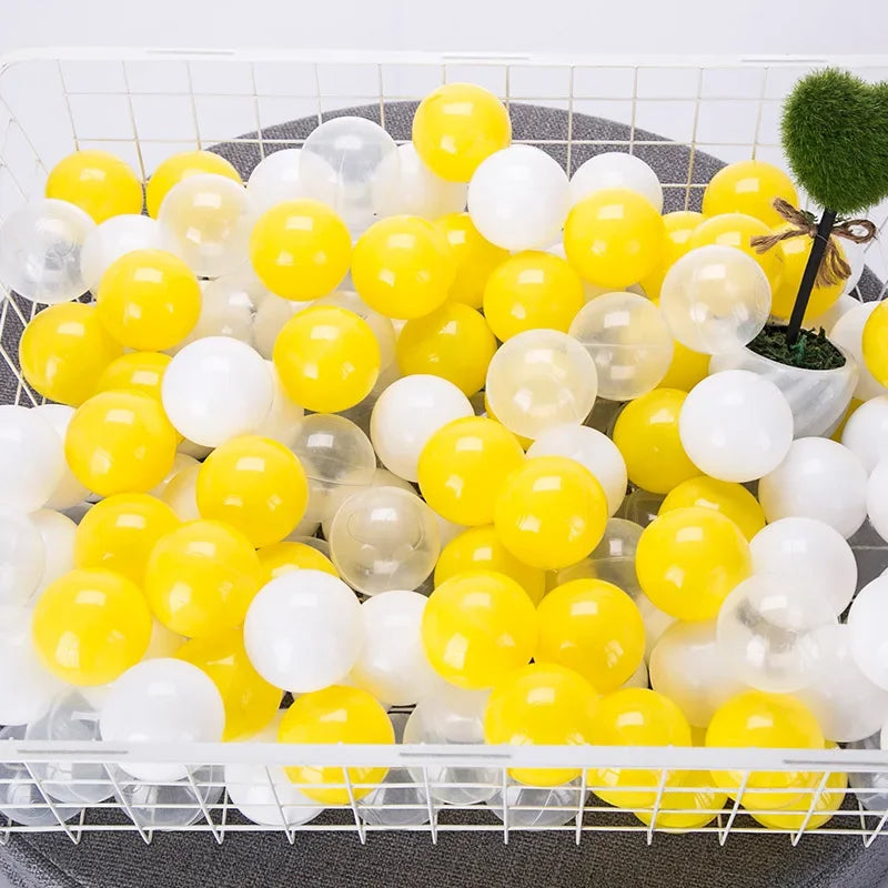 A tray filled with a mix of yellow and white clear and opaque plastic star-shaped balls for play.