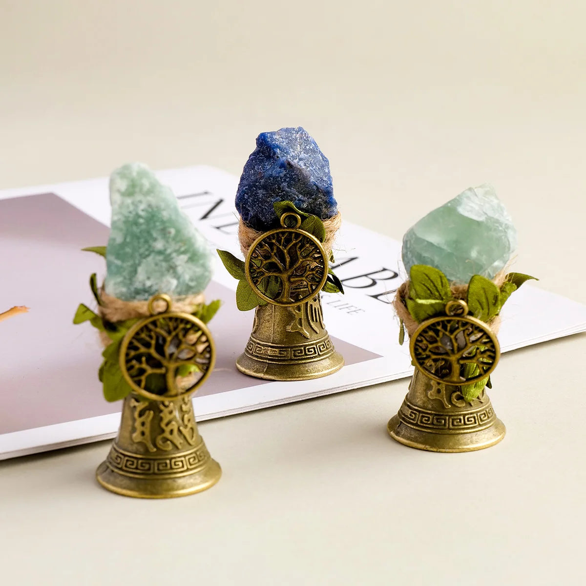 Three natural crystal specimens are displayed in brass bells with a copper finish.