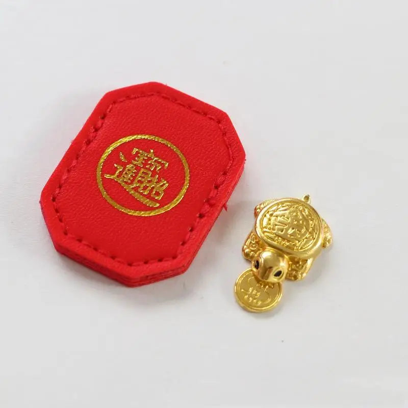A red felt tag with a gold circular emblem and a small golden tortoise figurine.
