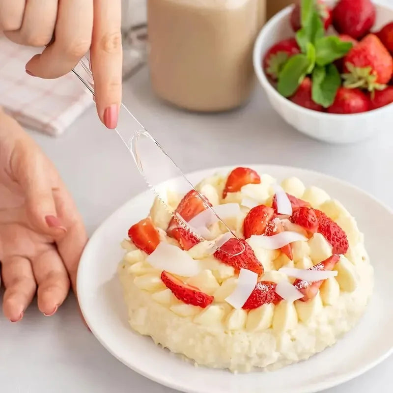 A plate of strawberry cream dessert with sliced strawberries and white shavings, next to a hand holding a plastic cutlery set