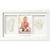 A white framed art print featuring three handprint and footprint impressions on a light background.