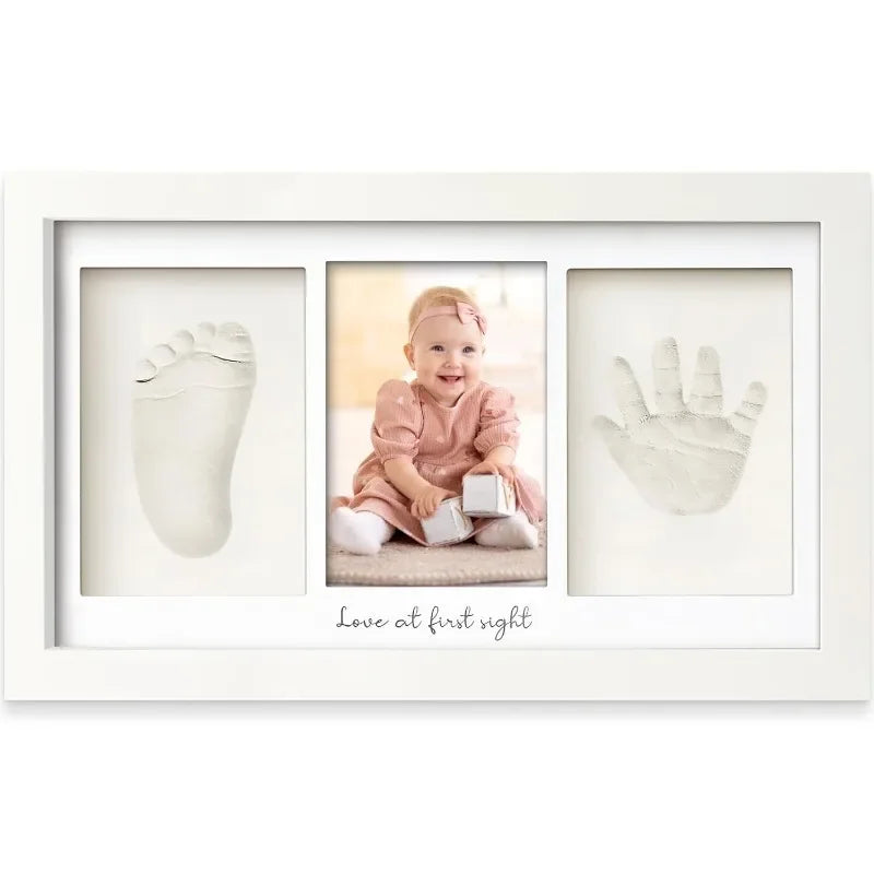 A white framed art print featuring three handprint and footprint impressions on a light background.