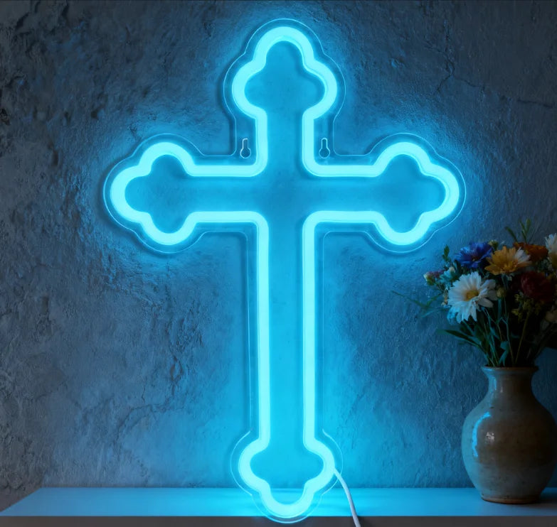 A bright blue neon cross wall sign mounted on a gray textured wall.