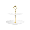 A gold two-tier serving stand with white scalloped dishes for desserts and fruit.