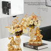 A pair of golden swan ceramic vases displayed on a white table with floral arrangements.