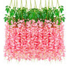 A dense display of pink artificial wisteria flowers hanging down, surrounded by green foliage.