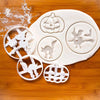 A set of white 3D Halloween cookie cutters and fondant stamps shaped like pumpkins, ghosts, and bats on a wooden surface.