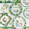 A green and white dinosaur party disposable tableware set with a banner and balloons displayed on a white surface.