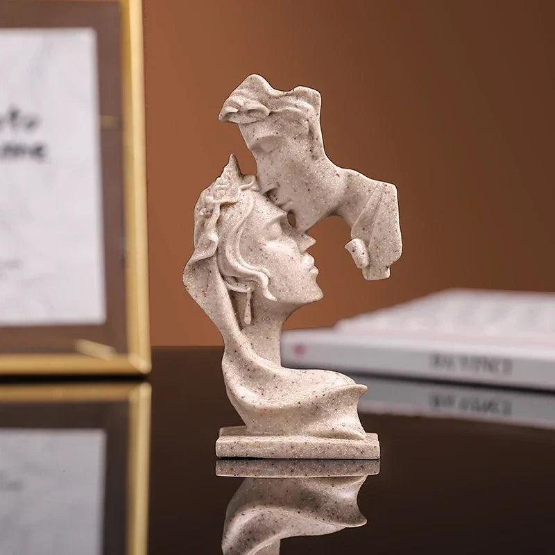 Une petite statue en résine de couleur claire représentant deux visages s'étreignant, présentée sur une surface réfléchissant