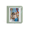A light green photo album with a clear window displaying a picture of two women smiling outdoors.