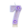 A purple sparkling number candle shaped like the number 7 with a flower decoration.