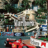 A red and white Marlboro Formula 1 race car is shown on a track with a grand building in the background.