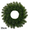 A green artificial Christmas wreath with red berries and a velvet bow.