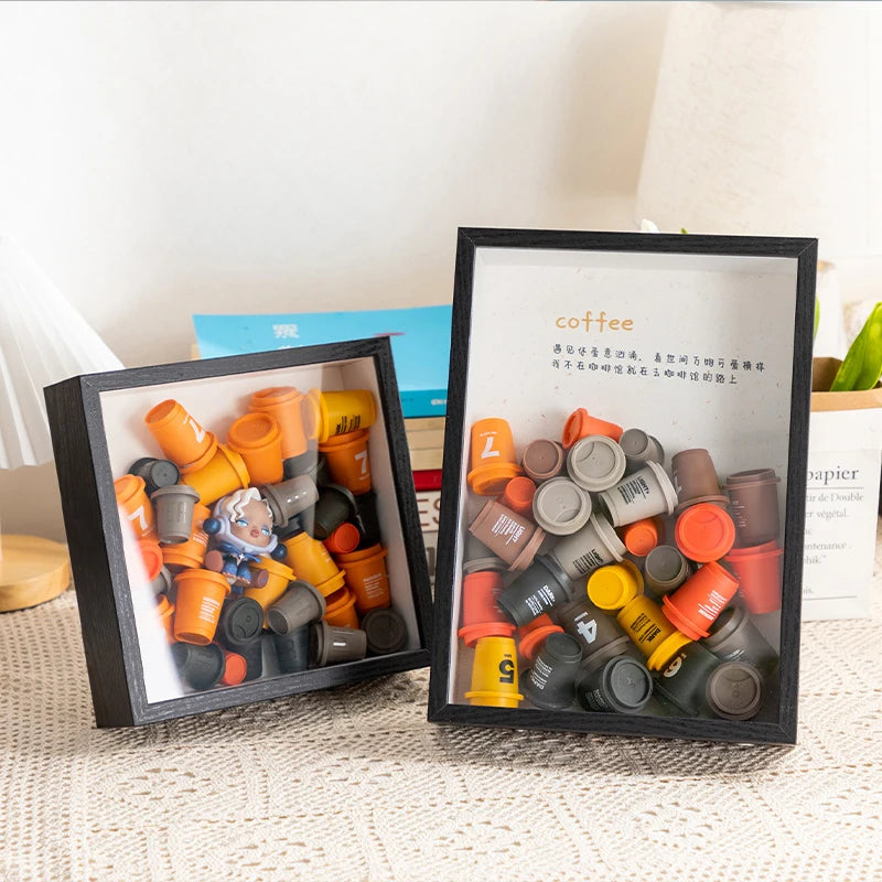 Schwarzer Bilderrahmen mit orange-grauen Kaffee-Bastelmaterialien.