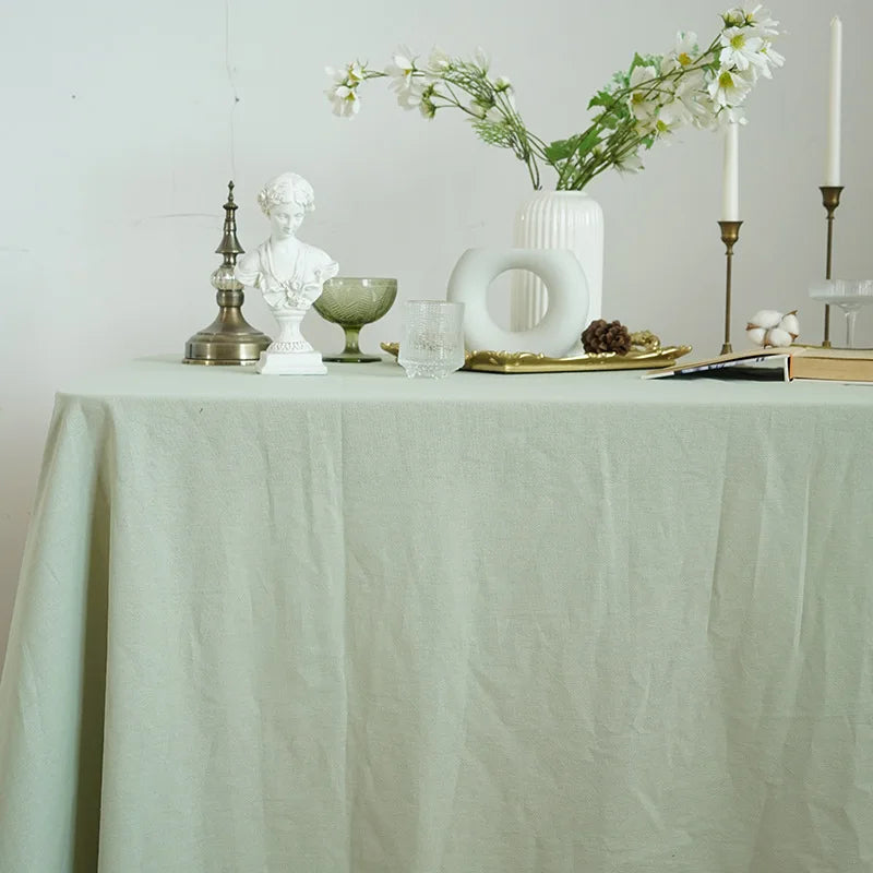 A light green cotton rectangle tablecloth set for dining and events with white decor.