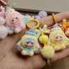 A hand holds several cute heart plush keychain charms in pastel colors like pink, yellow, and purple.