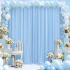 A light blue fabric party backdrop featuring vertical pleats and decorated with round balloons and white floral arrangements.