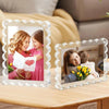A magnetic acrylic photo display frame showing a mother and daughter hugging, with a floral arrangement nearby.