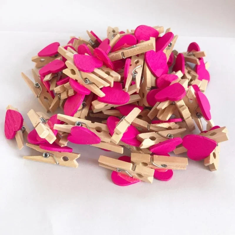 A pile of small pink and magenta wooden photo clips used for crafts and display.