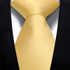 A close-up of a yellow silk necktie tied in a knot against a black suit jacket.