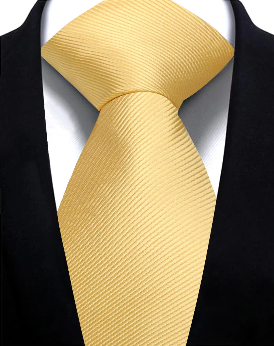 A close-up of a yellow silk necktie tied in a knot against a black suit jacket.