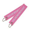 Pink woven keychain with the text Kiss Me Before Flight