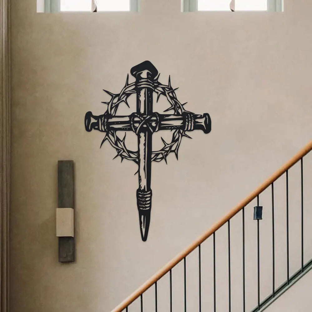 Black metal cross wall art with thorn details mounted on a beige wall above a wooden railing.