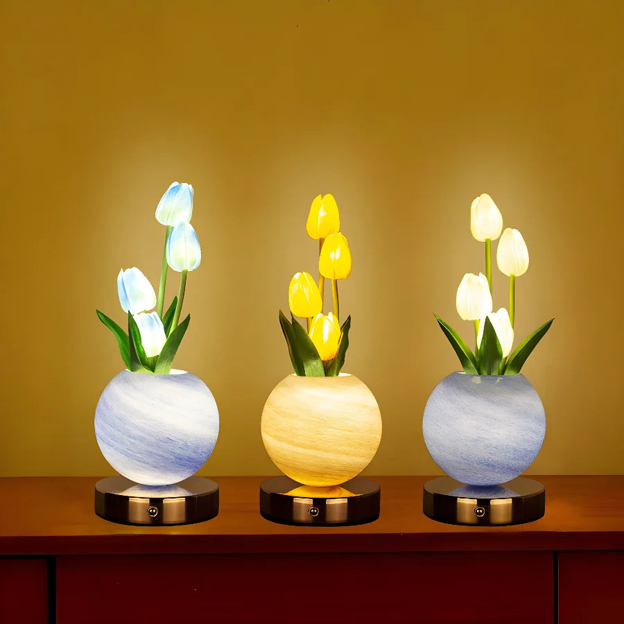 Three glass vases hold white and yellow tulips, illuminated by a warm light against a golden background.