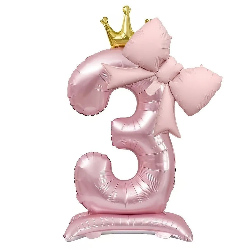A foil balloon shaped like the number 3 in pink with a gold crown topper
