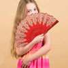 A girl holds a red and gold folding fan with traditional Chinese design.