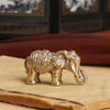 Antique bronze elephant figurine with detailed texture resting on a light wooden surface.