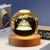 A round amber crystal ball decoration with a dark interior and gold lettering resting on a wooden base.