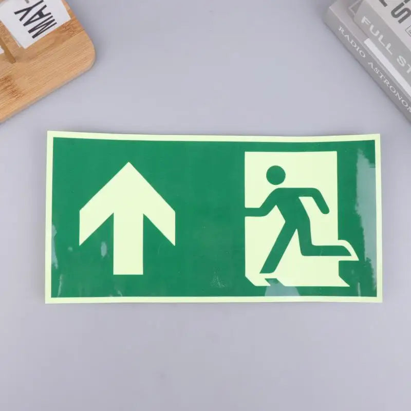 A rectangular photoluminescent emergency exit sign decal with a white upward arrow and a silhouette of a person walking.