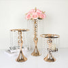A gold crystal flower centerpiece stand with cascading crystal strands and pink roses.