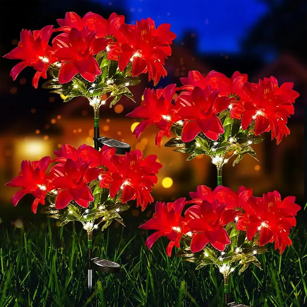 Red poinsettia garden lights illuminating flowers in a nighttime outdoor setting.