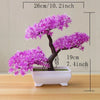 A small artificial tree bonsai decoration with vibrant purple flowers planted in a white rectangular pot.