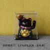 A black and gold solar-powered waving lucky cat figurine displayed in a clear box.