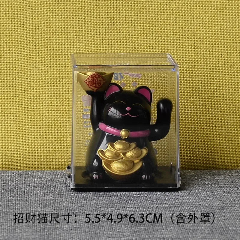 A black and gold solar-powered waving lucky cat figurine displayed in a clear box.
