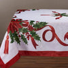 A white tablecloth featuring a red poinsettia and holly pattern with green leaves and red berries.