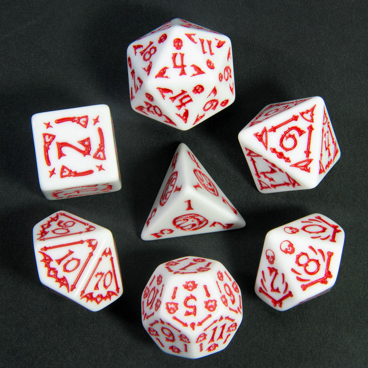 A collection of seven white polyhedral dice with red markings scattered on a dark surface.