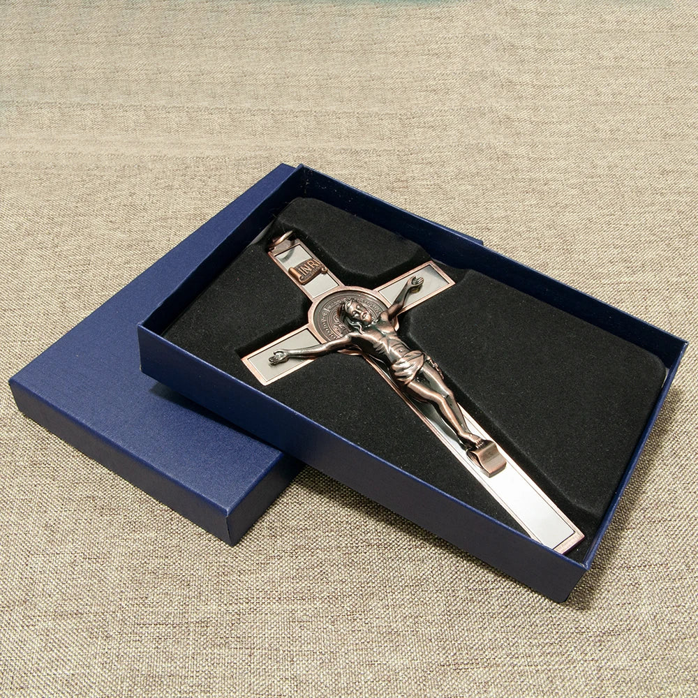 A silver crucifix with a figure of Christ inside, set in a dark blue velvet box for wall decor.