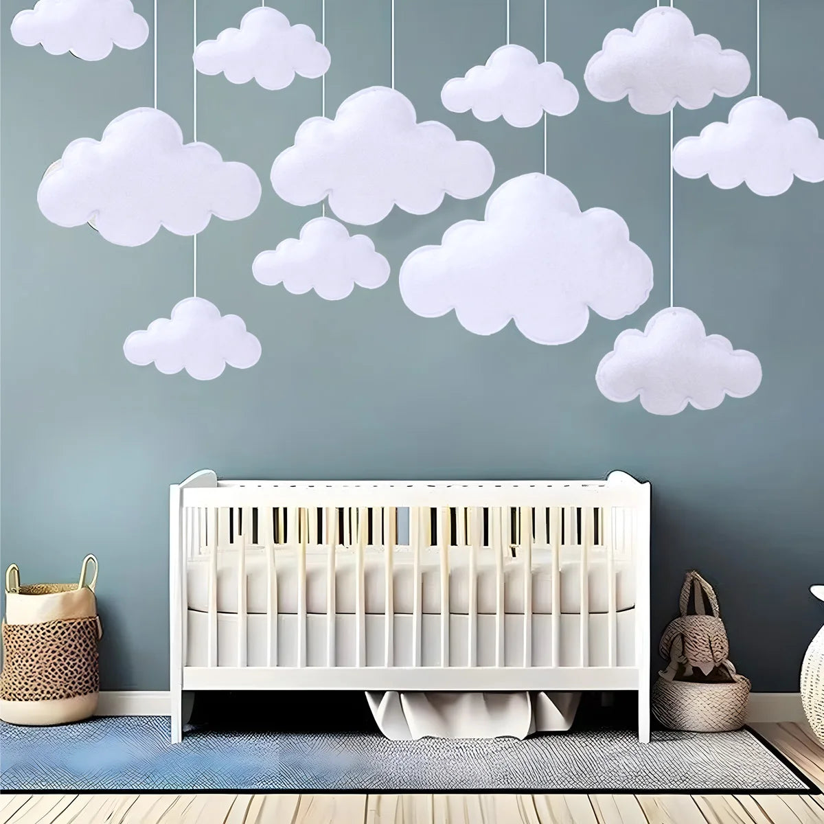 White cloud felt hanging decorations displayed against a gray wall above a crib.
