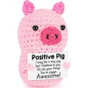 A pink crocheted pig toy with a positive message card attached.