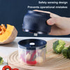 A hand holds a dark blue electric mini food chopper with a safety sensing design, positioned above a glass container filled w