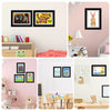 A collection of wooden picture frames displaying various drawings and photos on a pink wall.