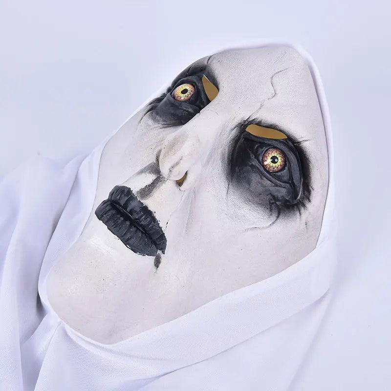A white face painted like a scary nun with dark eyes and a black latex mask and headscarf.
