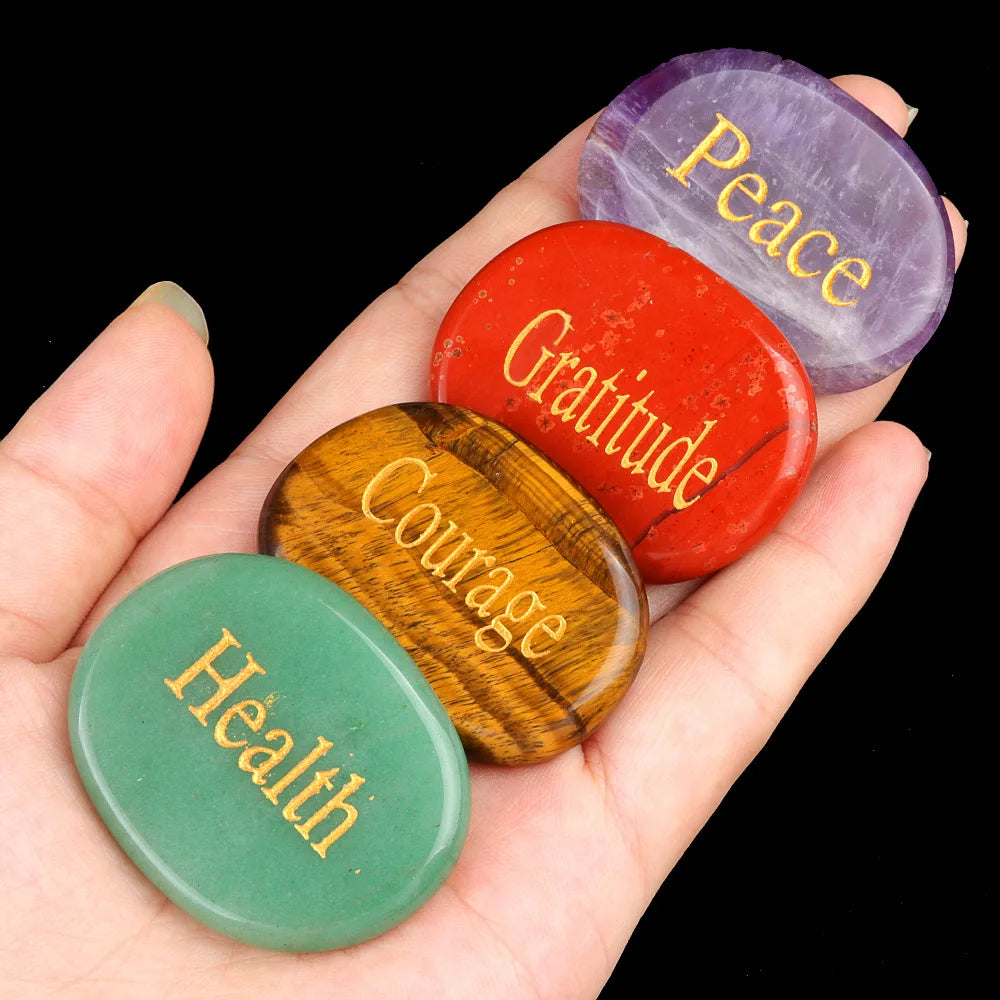 A hand holds five polished natural crystal ellipses in shades of purple, red, green, and amber.